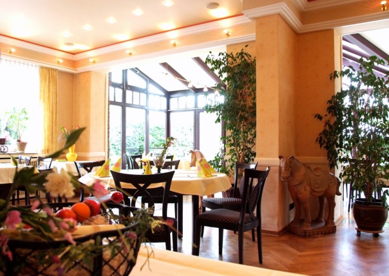 einladendes Restaurant mit gelben Wänden und runden Tischen mit gelben Tischdecken und Servietten