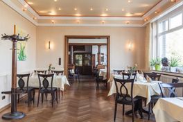 Restaurantbereich mit mehreren Tischen mit heller Tischdecke