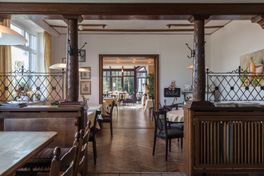 Restaurant mit braunen verzierten Säulen und mehreren gedeckten Tischen